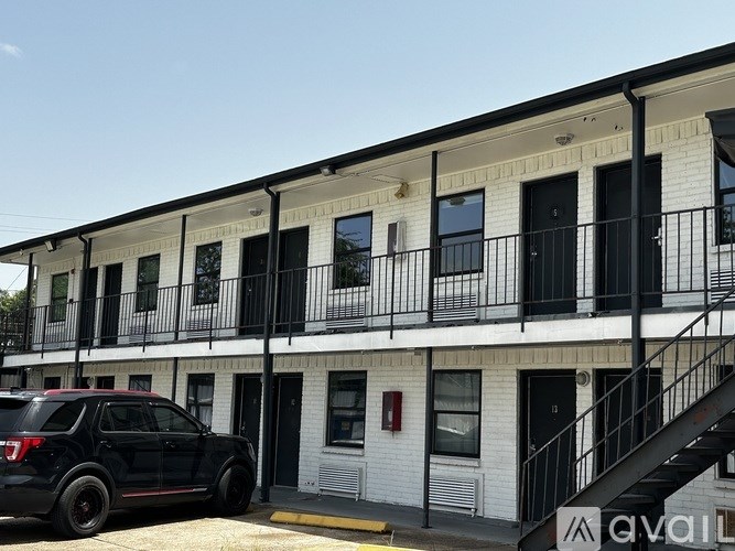 A black SUV is parked in front of a white building with black railings.