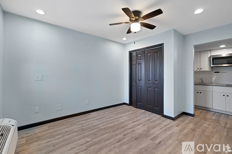 A room with a ceiling fan and a door leading to a kitchen.