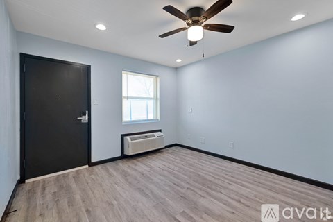 A room with a ceiling fan and a window with blinds.