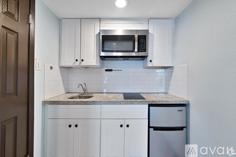 A kitchen with white cabinets and a granite countertop.