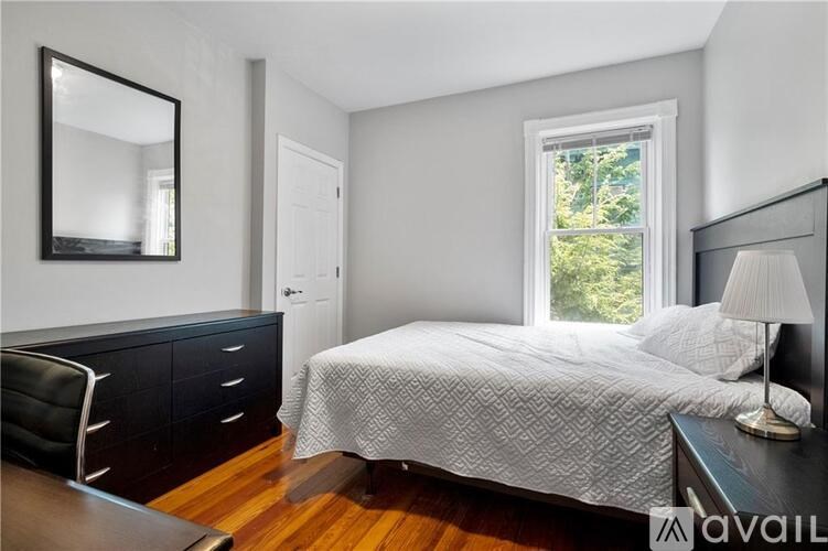 A bedroom with a bed, chair, and a mirror on the wall.