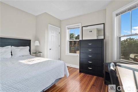 A bedroom with a large bed and a black dresser.