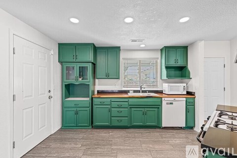 A kitchen with green cabinets and a white dishwasher.