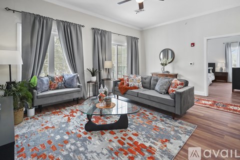 A living room with a grey couch, a glass coffee table, and a rug with a floral pattern.