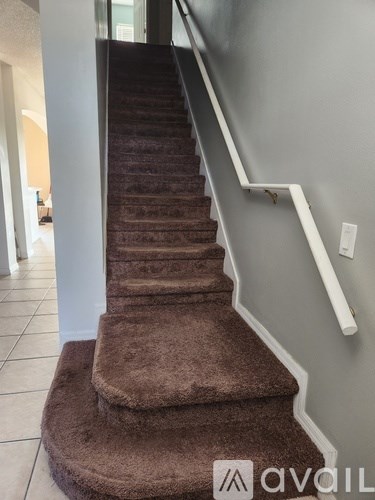 A staircase with a brown carpeted runner and white handrails.