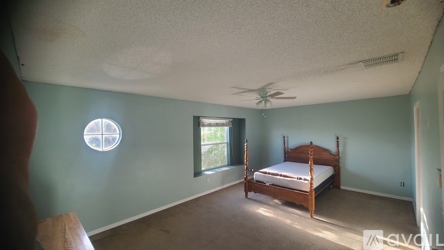 A bedroom with a bed, window, and ceiling fan.