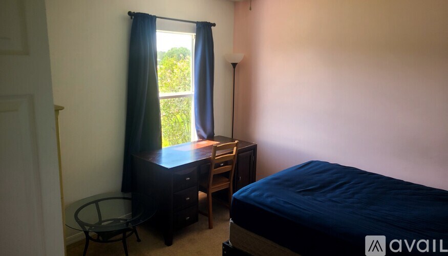 A bedroom with a bed, desk, chair, and window.