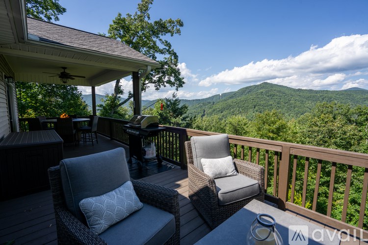 A balcony with two chairs and a table overlooking a mountainous landscape.