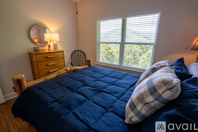 A bedroom with a bed, a dresser, and a window with blinds.