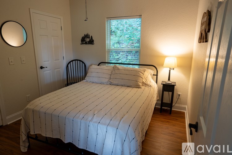 A bedroom with a bed, lamp, and window.