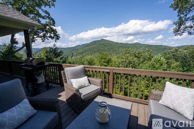 A balcony with two chairs and a table with a view of the mountains.