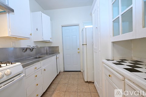 A kitchen with white cabinets and a black and white checkered floor.