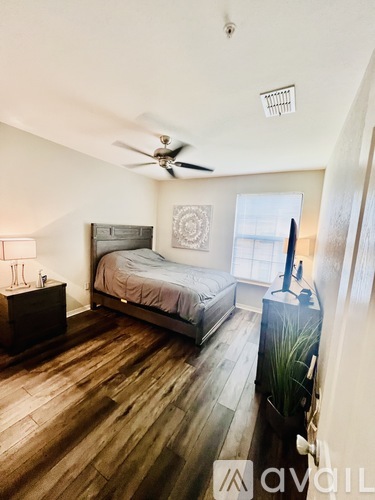 A bedroom with a bed, dresser, and ceiling fan.