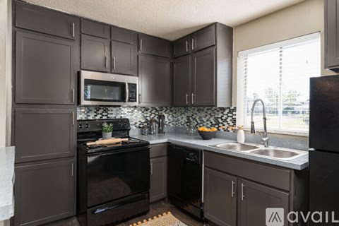 A kitchen with black cabinets and appliances.