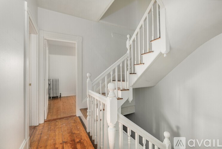 A white staircase with a wooden floor and a white wall.