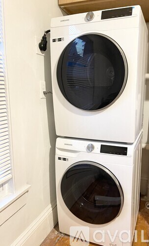 Two white front loading washing machines stacked on top of each other.