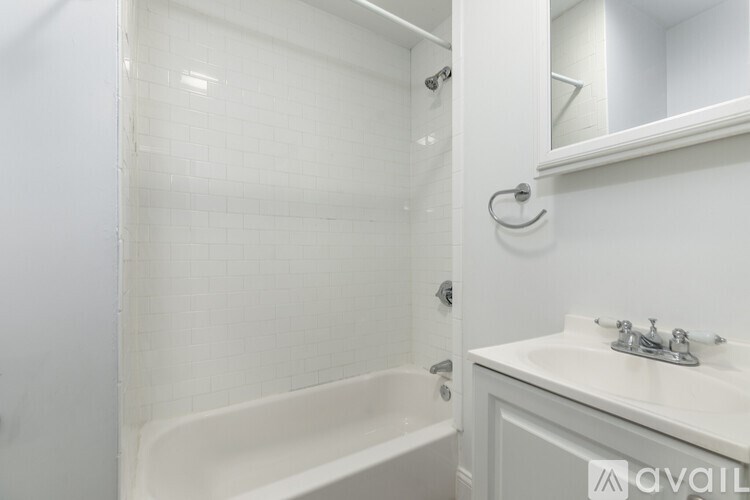 A white bathroom with a tub, sink and mirror.