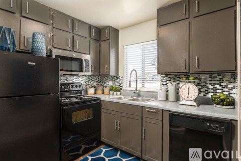 A kitchen with a black refrigerator and brown cabinets.