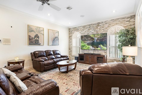 A living room with a brown leather couch and a stone wall.
