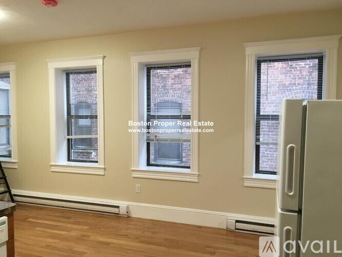 A room with three windows and a wooden floor.