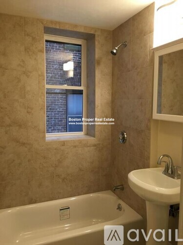 A bathroom with a tub, sink and window.