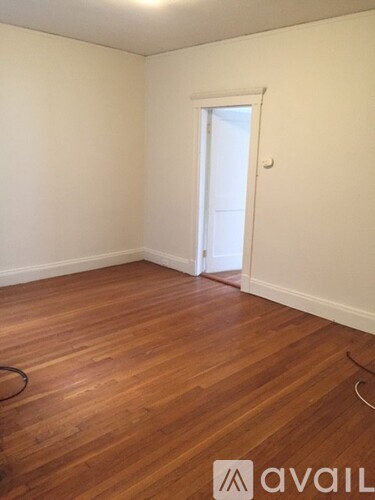 A room with wooden flooring and a doorway leading to another room.
