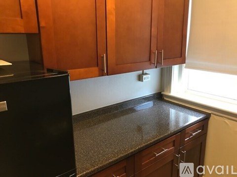 A kitchen with brown cabinets and a black refrigerator.