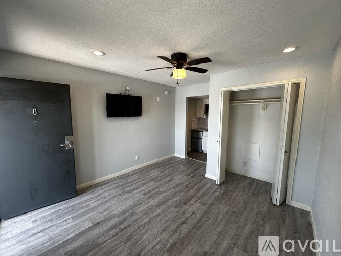 A room with a ceiling fan and a flat screen TV mounted on the wall.