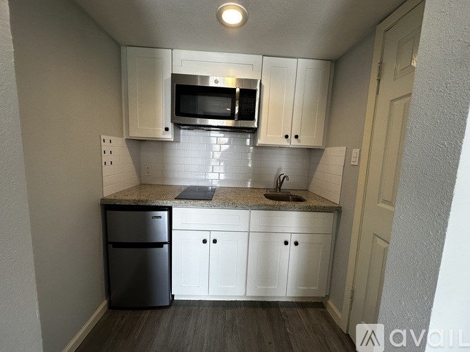 A kitchen with white cabinets and a black fridge.