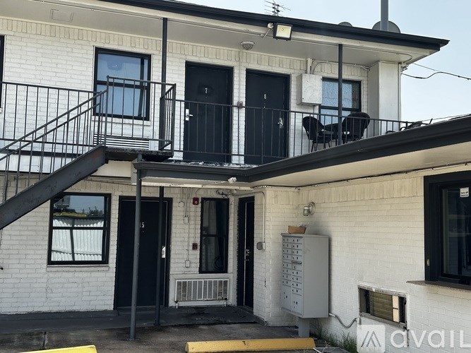 A white building with a black door and a balcony with a table and chairs.