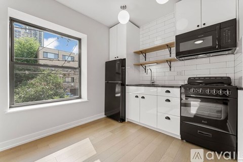 A kitchen with black appliances and white cabinetry.