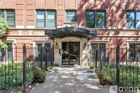 The entrance to a brick building with a black gate and a sign that reads "The Windale.".