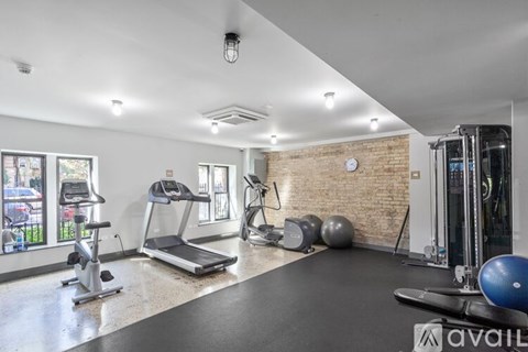 A well-lit gym with a variety of equipment including a treadmill, exercise ball, and weights.