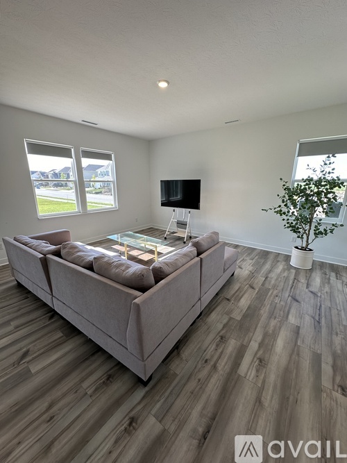 A living room with a grey sofa and wooden flooring.