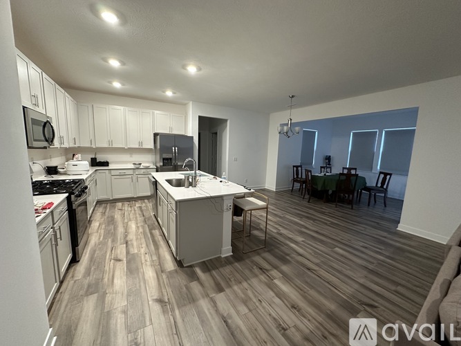 A spacious kitchen with white cabinets and a wooden floor.