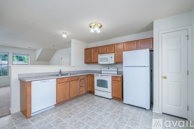 A kitchen with white appliances and wooden cabinets.