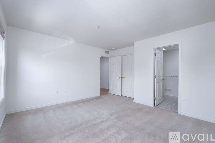 A spacious room with white walls and carpeted floor.