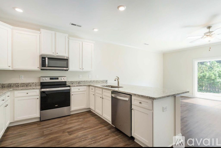 A kitchen with white cabinets and a wooden floor.