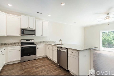 A kitchen with white cabinets and a wooden floor.