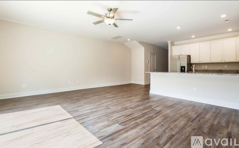 A spacious room with a ceiling fan and wooden flooring.