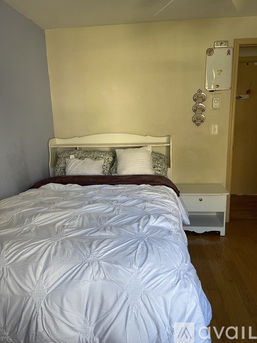 A bed with a white comforter and pillows in a room.