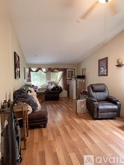 A living room with a brown leather chair and a brown couch with a blanket on it.