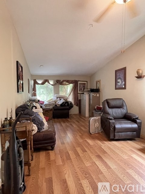 A living room with a brown leather chair and a brown couch with a blanket on it.