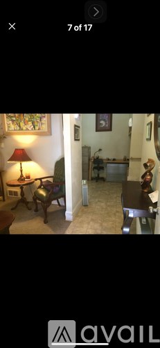 A living room with a couch, a chair, a lamp, and a painting on the wall.