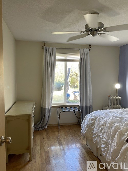 A bedroom with a bed, a dresser, and a window with curtains.