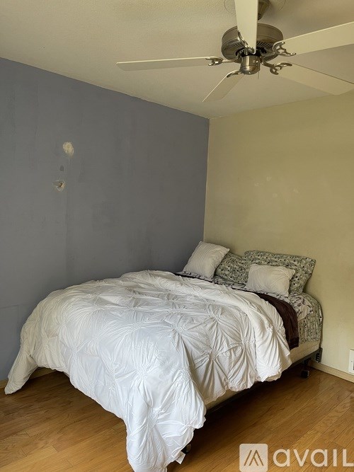 A bedroom with a bed and a ceiling fan.
