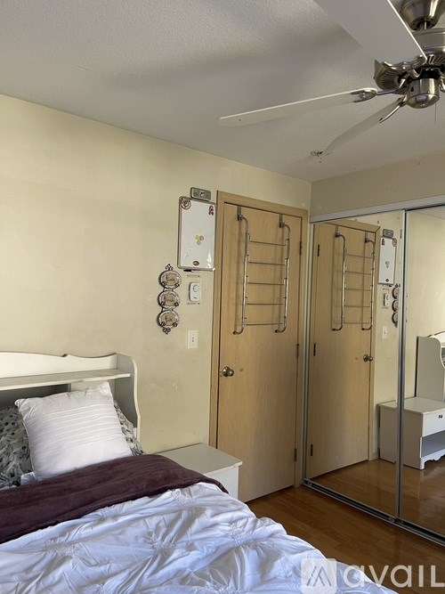 A bedroom with a bed, mirror, and fan.
