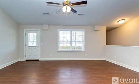 A spacious room with a ceiling fan and wooden flooring.
