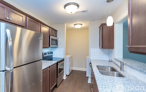 A kitchen with a stainless steel refrigerator and wooden cabinets.