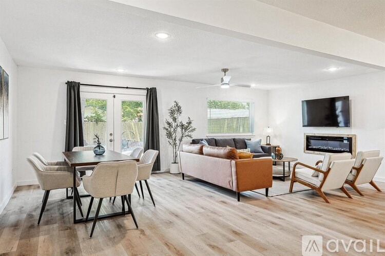 A living room with a television, a couch, a table, and chairs.